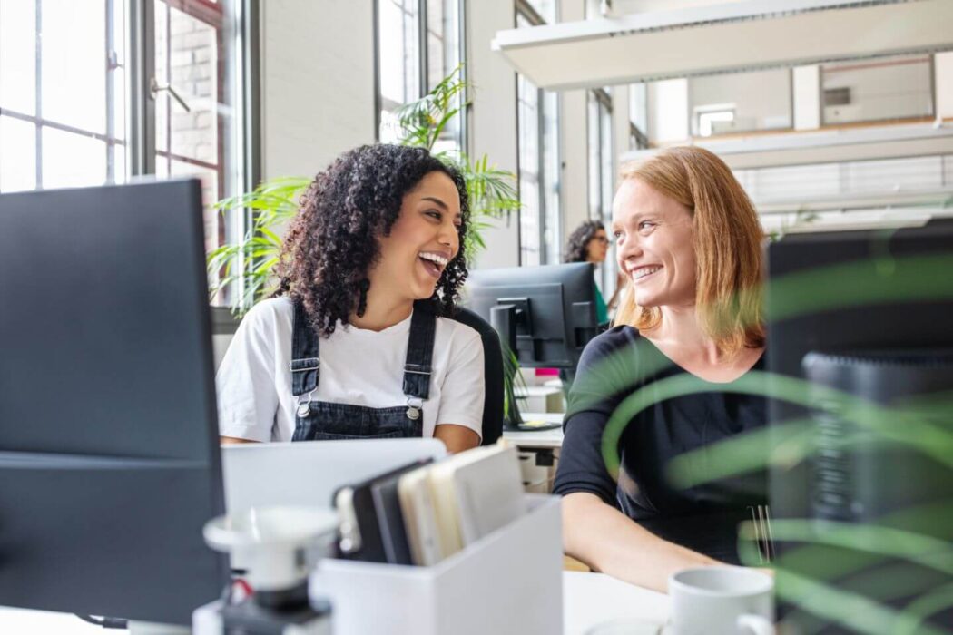 Two workers laughing at desks